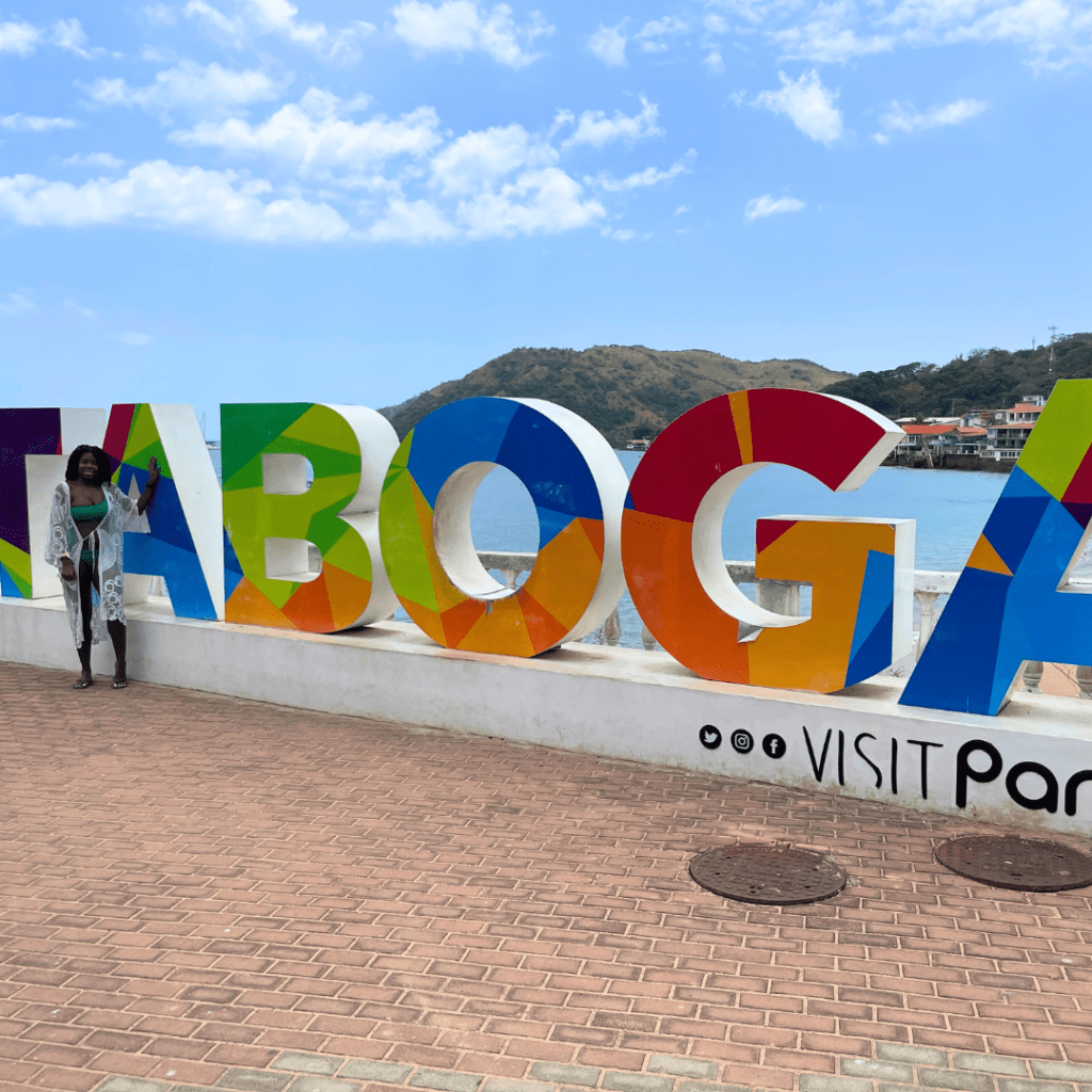Girl in swimsuit standing in front of Taboga Island sign