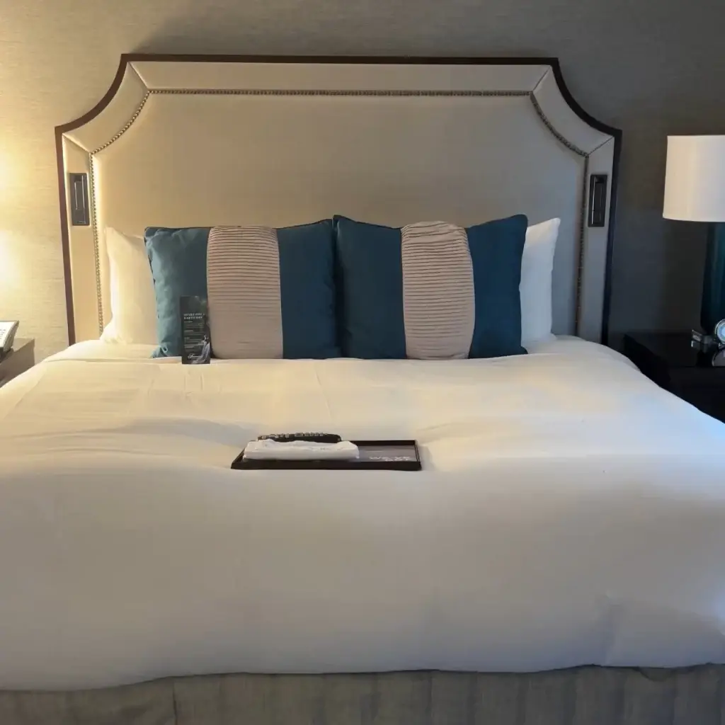King bed with white sheets and blue and white striped pillow