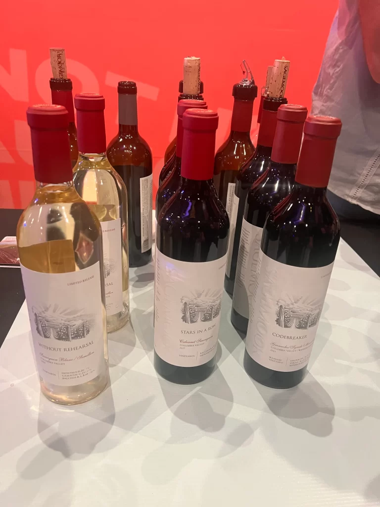 3 rows of wine bottles lined up on white table cloth. 