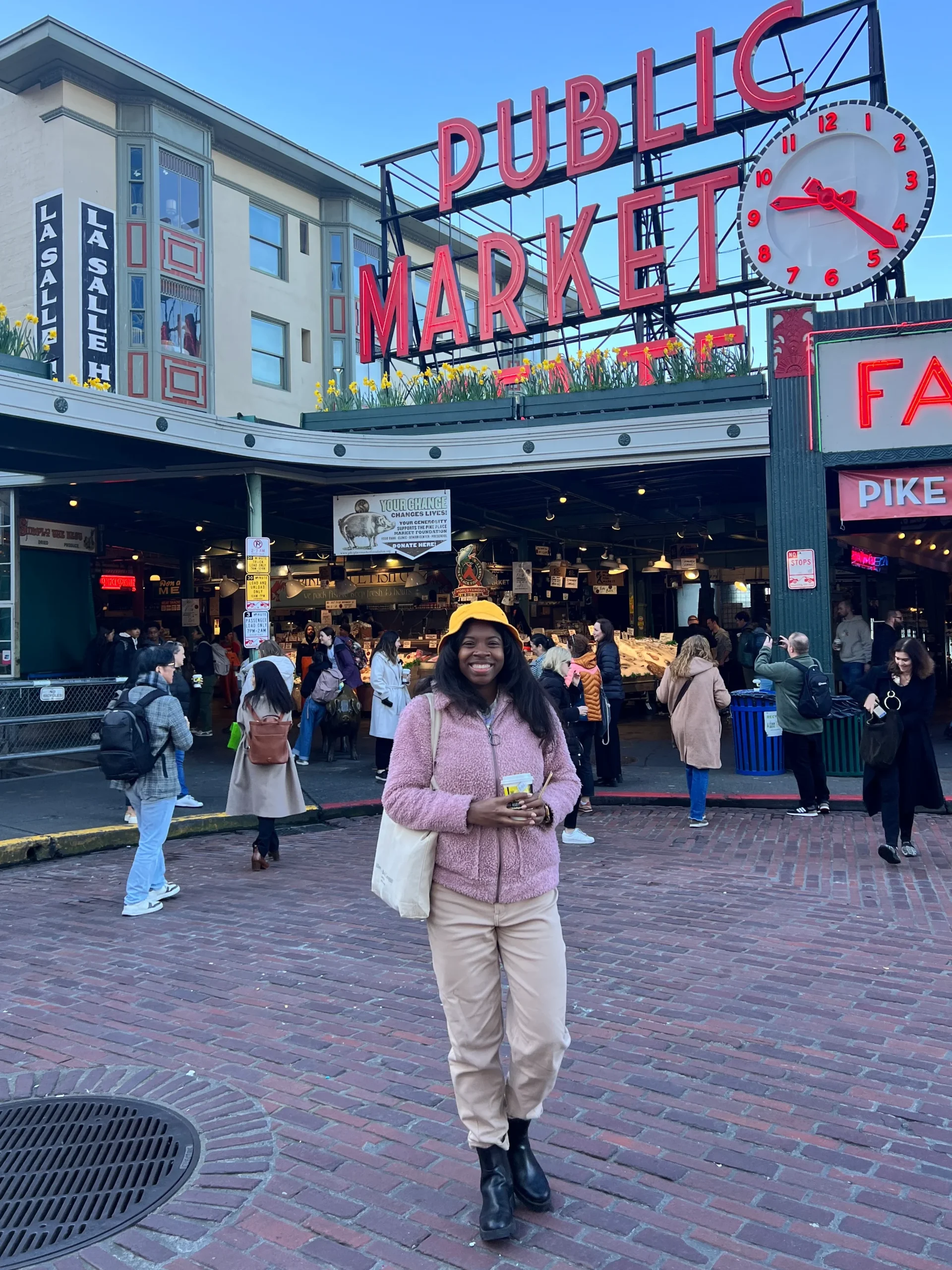 Robin Denise standing in front of Pike Place Market sign